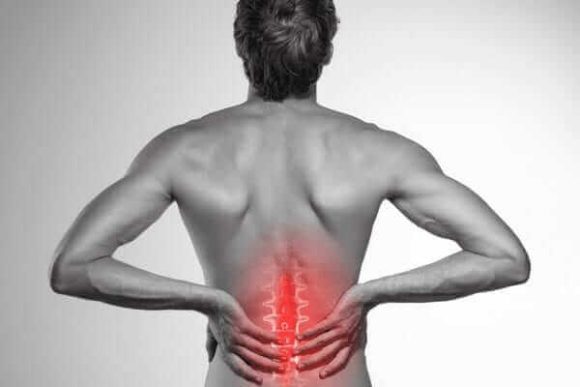 Man holding his lower back in pain, highlighting the need for orthopedic spine surgery